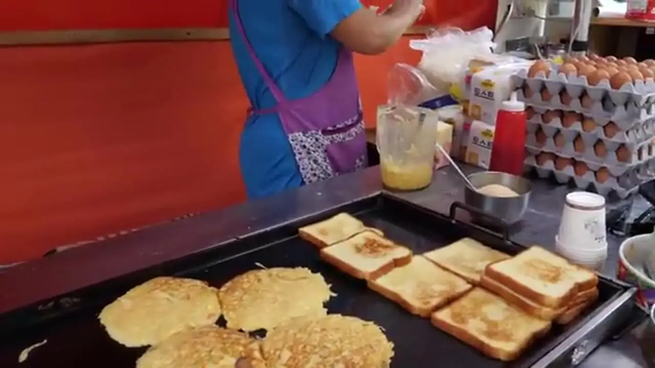 غذای خیابانی در کره؛ تهیه ساندویچ نان تست با تخم مرغ، کالباس و پنیر در سئول